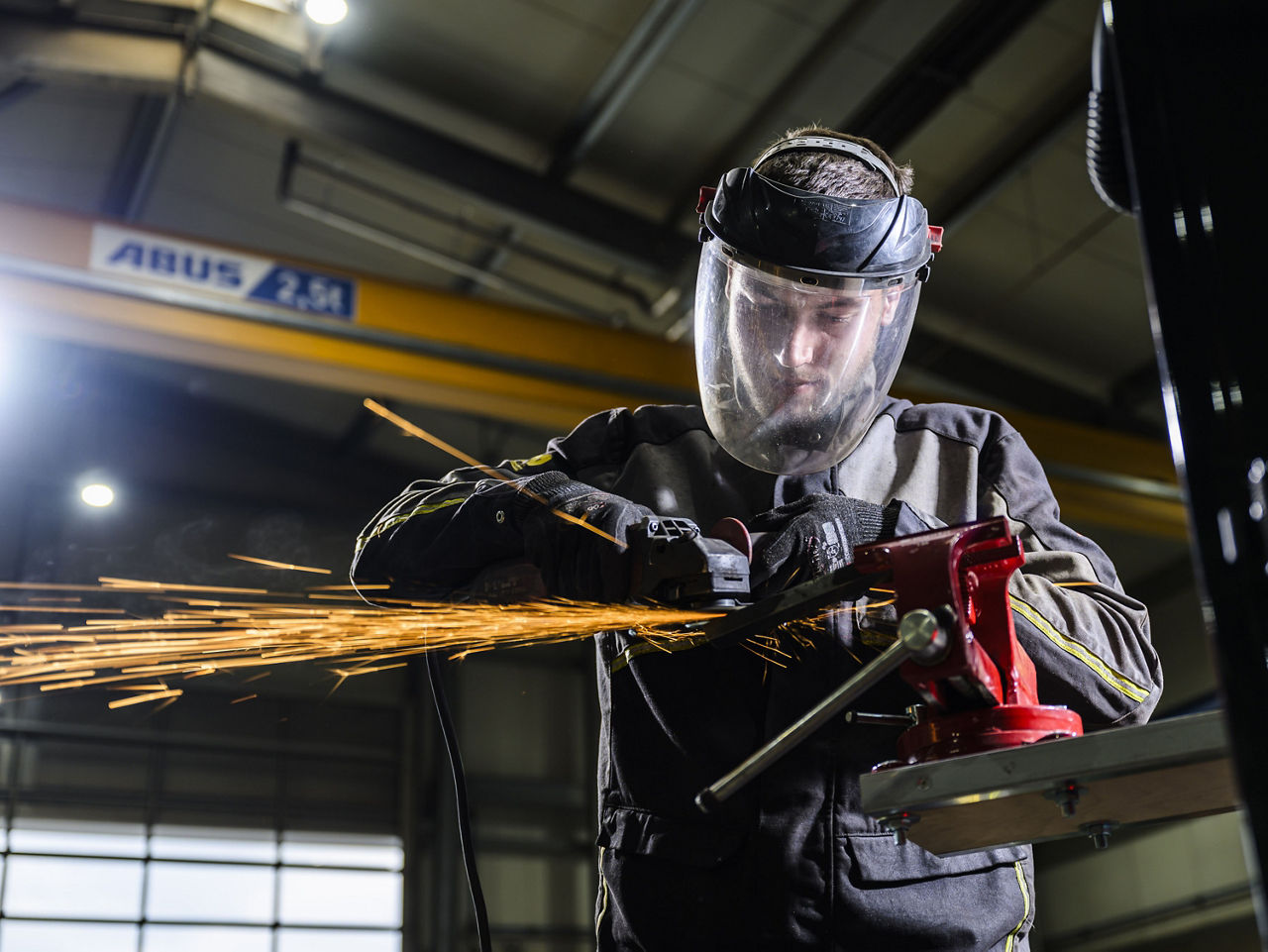 In Schutzkleidung repariert ein Arbeiter der Firma Nett mit einer Flex ein Metallteil.
